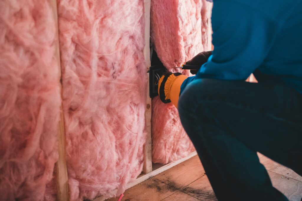 Man retrofitting social housing with pink insulation. Photo by Erik Mclean on Unsplash